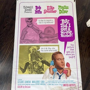 Puede incluir: Cartel de película vintage de "Boy, Did I Get a Wrong Number!" con Bob Hope, Elke Sommer y Phyllis Diller. El cartel tiene una combinación de colores rosa, verde y morado con imágenes de los actores y texto.