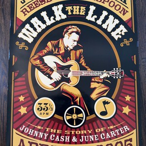 Pode incluir: Um cartaz em estilo vintage para o filme "Walk the Line" com Joaquin Phoenix e Reese Witherspoon. O cartaz apresenta uma imagem central de um homem tocando guitarra, com texto incluindo "Johnny Cash & June Carter" e a data "22 de abril de 2005".