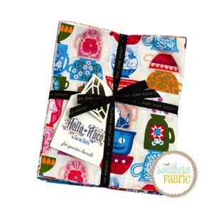 Op de afbeelding: Een bundel bedrukte stof met kleurrijke theekopjes in rood, blauw en groen. De stof is vastgebonden met een zwart lint en bevat een label met de tekst "Hello Alice".