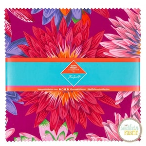 Può includere: Una pila di quadrati di tessuto con un vivace motivo floreale di grandi dalie rosse, rosa e viola su sfondo magenta. Una fascia di carta turchese avvolge il centro con il testo Kaffe Fassett Collective for FreeSpirit.