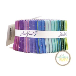 Puede incluir: Un rollo de tela con una variedad de estampados en morado, azul y verde con lunares blancos. La tela está etiquetada como "Free Spirit" y está enrollada con una cinta blanca.