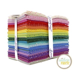 May include: A stack of colorful fabric squares with a white polka dot pattern. The fabric is bundled together with a white ribbon that says "Free Spirit" on it. The fabric is arranged in a rainbow pattern, with red, orange, yellow, green, blue, indigo, and violet squares. The fabric is from Southern Fabric.