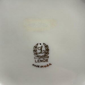 May include: A white ceramic plate with a gold Lenox logo and the words "Made in U.S.A."
