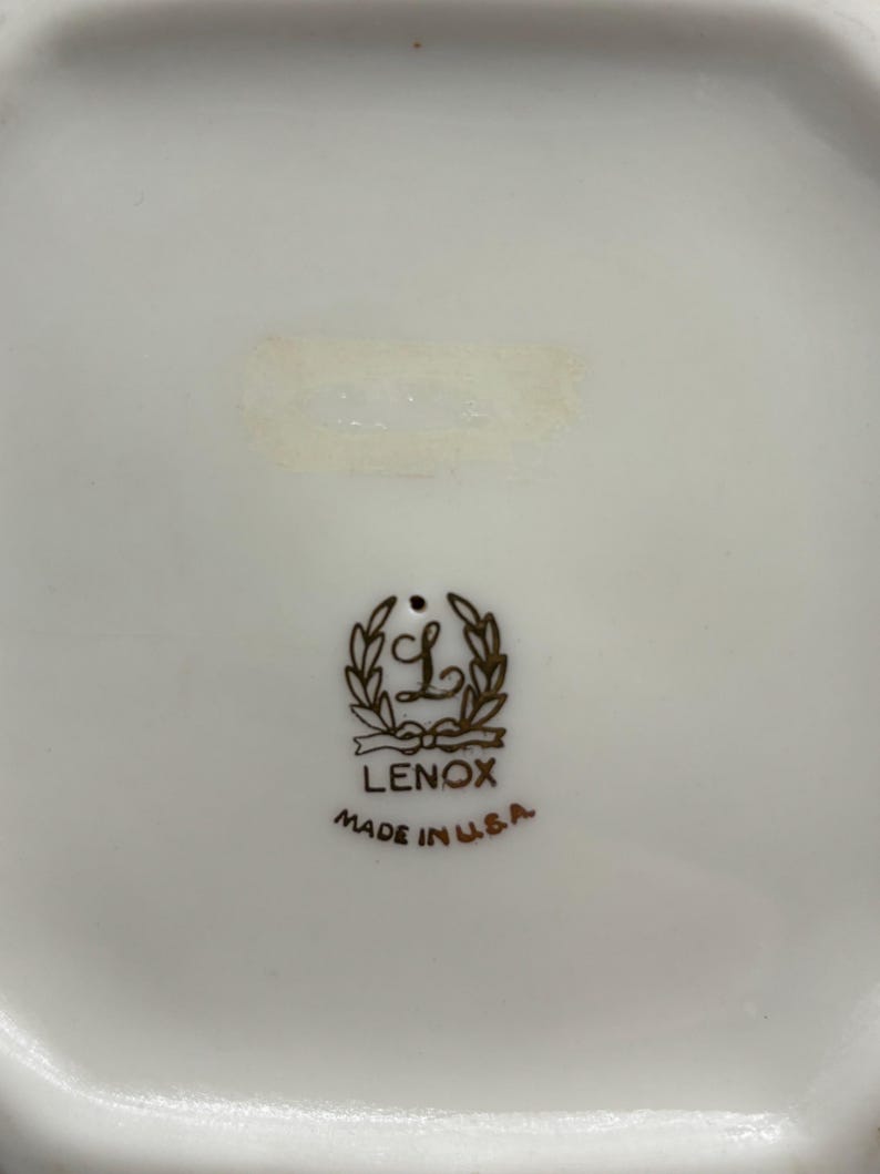 May include: A white ceramic plate with a gold Lenox logo and the words "Made in U.S.A."