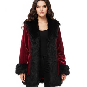 以下が含まれることがあります： 黒いフェイクファーのトリムが付いた、バーガンディ色のベルベットコート。コートは、広い襟、袖口、長いオープンデザインが特徴です。モデルは黒いパンツとブーツを着用しています。このコートは、スタイリッシュなアウターウェアです。