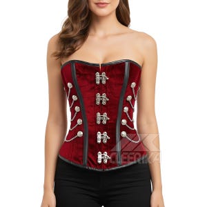 May include: A strapless burgundy corset with black trim and silver-coloured metal clasps and chain detailing. The corset has a velvet-like texture and is designed to cinch the waist. The garment is a fashion item.