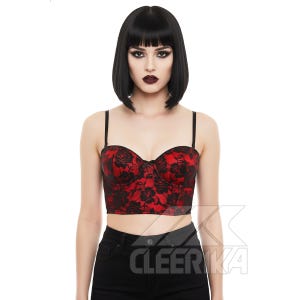 Puede incluir: Un top bustier rojo y negro con una superposición de encaje floral. El top tiene finas correas negras y un escote corazón. La palabra "CLEERIKA" está impresa en blanco en la esquina inferior derecha.