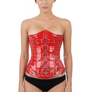 May include: A red, strapless corset with a glossy finish. The corset features silver-toned metal rings and rivets, and a structured design. The garment is worn with black underwear.