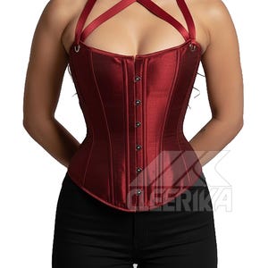 May include: A burgundy corset with a halter neck design. The corset has a satin-like sheen, a row of buttons down the front, and a structured silhouette. The halter straps cross at the chest.