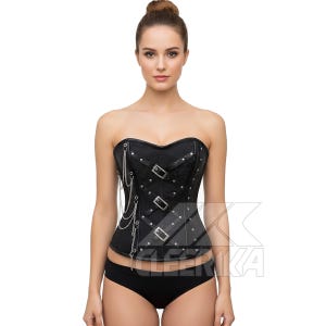 May include: Black strapless corset featuring silver-tone metal buckles, rivets, and chain detailing. The corset has a textured pattern and is designed to cinch the waist. The garment is paired with black underwear.