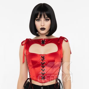 May include: A red satin corset with a heart-shaped cutout and black lacing. The corset has tie closures at the shoulders and waist. The garment is a bold fashion statement.