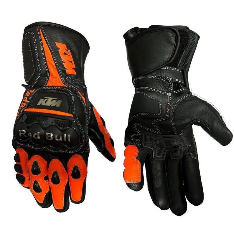 May include: A pair of black and orange motorcycle gloves featuring the KTM logo and Red Bull branding. The gloves include protective knuckle guards, reinforced stitching, and adjustable wrist straps for a secure fit on both hands.
