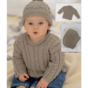 May include: A baby wearing a knitted taupe sweater and matching hat with a pom-pom. The sweater has a textured cable knit design. The baby is also wearing blue jeans. Additional images show the sweater and hat separately.