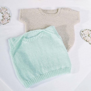 May include: Two knitted baby tops. One is a light beige color, and the other is a soft mint green. The tops have a round neckline and short sleeves. The knitwear is made of a soft, textured yarn, perfect for a baby's delicate skin.