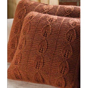 May include: Two rust-colored knitted throw pillows with a textured, patterned design. The pillows have a repeating vertical pattern of oval shapes with a leaf-like design in the center. The pillows are soft and plush, perfect for adding comfort and style to any living space.