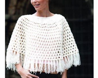 Puede incluir: Poncho de crochet crema con tejido abierto y flecos en el borde inferior. El poncho tiene un cuello redondo y un diseño suelto y fluido. Los flecos miden aproximadamente 10 cm de largo. La prenda está hecha de un hilo suave y texturizado.