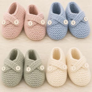 May include: A collection of six knitted baby booties in pastel colors: pink, blue, green, and cream. Each pair features a cross-over design secured with a white button. The booties are arranged on a soft, light-colored surface.