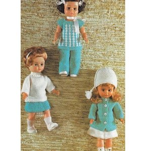 Peut inclure: Trois poupées vintage vêtues de tenues tricotées. L'une porte un haut rayé bleu et blanc et un pantalon assorti. Une autre poupée est dans un pull blanc et une jupe bleue. La troisième poupée porte une veste bleue, une jupe blanche et un chapeau blanc.