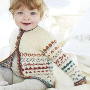 May include: A cream-coloured baby cardigan with a patterned design on the sleeves and lower front. The knitwear features brown, red, and teal accents. The cardigan has a button closure and a round neckline.