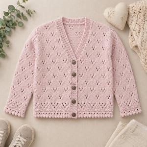 Peut inclure: Un cardigan rose clair en tricot avec un col en V et une fermeture boutonnée. Le pull présente un motif ajouré délicat et des bords festonnés. Les manches longues et le corps sont ornés d'un motif en forme de losange. Le cardigan a six boutons.