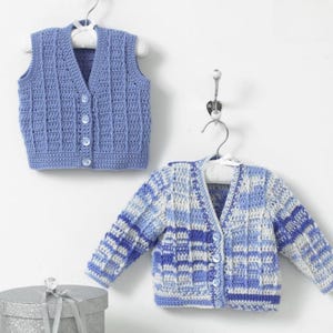 May include: Two baby crochet garments: a blue vest and a long-sleeved cardigan. The vest is a solid light blue, button-down style. The cardigan features a mix of blue and white squares, also with buttons. Both are hanging on white hangers.