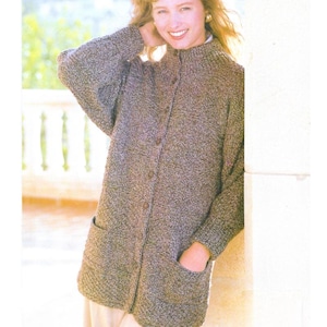 Puede incluir: Un cárdigan de punto texturizado marrón y gris con cuello alto y cierre de botones. El cárdigan tiene dos bolsillos delanteros y mangas largas. La mujer lleva el cárdigan.