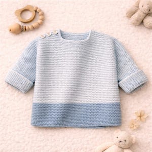 Könnte beinhalten: Hellblau-weiß gestrickter Baby-Pullover mit drei kleinen Knöpfen auf der Schulter. Der Pullover hat lange Ärmel mit umgeschlagenen Manschetten. Ein Beißring aus Holz und ein Teddybär sind ebenfalls im Bild.