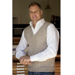 May include: A light brown cable-knit sweater vest with a V-neck, worn over a white collared shirt. The vest has a textured cable design down the front. The person is wearing blue jeans.
