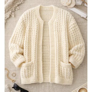 Peut inclure: Cardigan crème à devant ouvert avec deux poches avant. Le pull en tricot épais présente un motif texturé et des manches trois-quarts. Le vêtement est fait d'une matière douce et chaude.