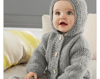 May include: A gray, hand-knitted baby cardigan and hood set. The hooded sweater has a button-up front with three wooden buttons. The set is made of a chunky knit yarn. The baby is wearing the sweater and hood.