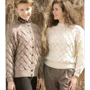 May include: Two women in knitted sweaters. One wears a beige cardigan with a diamond pattern and dark buttons. The other wears an off-white sweater with a similar diamond pattern. Both sweaters have a textured, woven appearance.