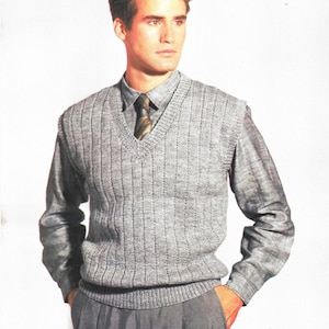 Peut inclure: Un gilet de costume gris en maille côtelée avec un col en V, superposé à une chemise grise boutonnée et une cravate. Le gilet présente un motif côtelé vertical. L'ensemble est complété par un pantalon gris. Le style est classique et preppy.