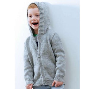 Può includere: Un cardigan con cappuccio in maglia grigio chiaro con bottoni. Il cardigan presenta polsini e orlo a coste. Il bambino indossa una camicia verde sotto. Il cardigan è un'opzione di abbigliamento esterno comoda ed elegante.