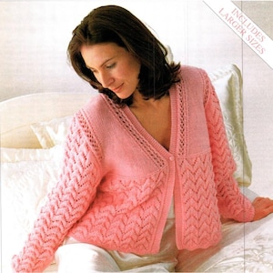 May include: A light pink knitted cardigan with a V-neck and long sleeves. The sleeves and lower front panels feature a textured, openwork design. The cardigan is buttoned and appears to be made of a soft, warm material. The text "INCLUDES LARGER SIZES" is visible.