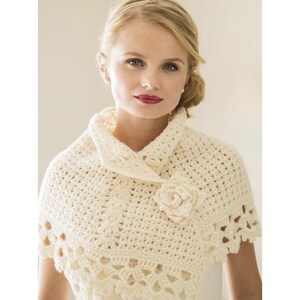 May include: Cream-colored crochet shawl with a floral accent. The shawl features a textured, openwork design and a decorative flower on the front. The shawl is worn over the shoulders and has a collar-like neckline.