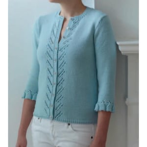 May include: A light blue cardigan with a round neckline and three-quarter sleeves. The cardigan features a button-down front and a decorative openwork design down the center. The sleeves have a ruffled edge. The cardigan is paired with white pants.