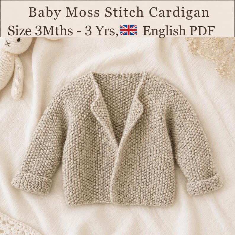 May include: A beige knit cardigan with a moss stitch texture, long sleeves, and folded cuffs. The text reads: Baby Moss Stitch Cardigan, Size 3Mths - 3 Yrs, English PDF. A small white plush toy is partially visible in the upper left corner.