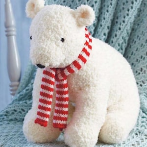 Peut inclure: Une peluche d'ours polaire blanc avec un petit nez et des yeux noirs, portant une écharpe rayée rouge et blanche. L'ours est assis, avec sa fourrure duveteuse visible. Un jouet mignon et câlin.