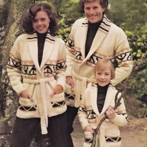 Könnte beinhalten: Drei Personen tragen passende cremefarbene Strickjacken mit geometrischen Mustern in Schwarz, Beige und Braun. Die Strickjacken haben Schalkragen, Taschen und Taillengürtel. Sie tragen schwarze Rollkragenpullover und dunkle Hosen.