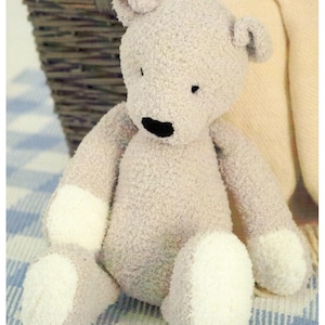 May include: A plush teddy bear in a seated position. The bear is light gray with white accents on its paws and feet. It has a black stitched nose and small black eyes. The bear is made of a soft, textured material.