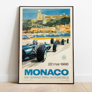 May include: Vintage Monaco Grand Prix poster from 1966, featuring two race cars speeding on a track. The poster has a blue, orange, and white color scheme, with a coastal town and a castle in the background. The text "MONACO" is prominently displayed.