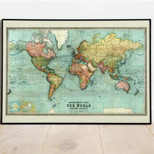 May include: Framed vintage world map print. The map features a detailed depiction of the continents in various colors, set against a light blue background. The map is framed in a black border and includes the text "Bartholomew's Chart The World".