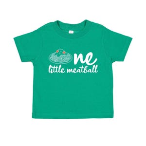 May include: A green toddler t-shirt with the words "one little meatball" in white script. The design includes a graphic of spaghetti and meatballs. The shirt is made of a soft material.