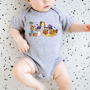 May include: A gray baby onesie featuring a colorful Halloween-themed graphic. The graphic includes cartoon characters dressed in costumes, such as a ghost, a pirate, and a pumpkin. The onesie is short-sleeved and has a simple, classic design.