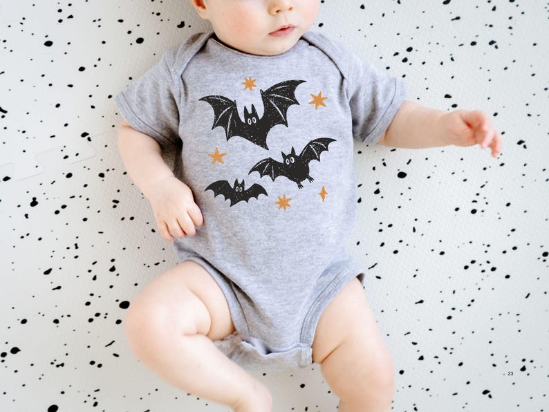 May include: A heather gray short-sleeve baby bodysuit featuring a graphic print of three black bats and four small orange stars. The garment has a round neckline and a snap-button closure at the bottom, designed for infants with a simple, functional fit.