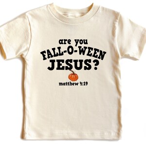 May include: Cream-colored t-shirt with the text "are you FALL-O-WEEN JESUS?" in black, with a small orange pumpkin graphic. Below the text is "matthew 4:19" in black. A fun, seasonal tee for the fall.