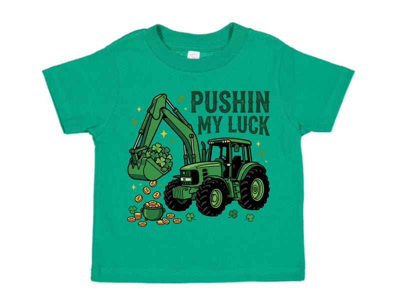 May include: A green toddler t-shirt featuring a green tractor with a bucket full of shamrocks and gold coins. The text "PUSHIN MY LUCK" is printed above the tractor. The design is in a cartoon style.