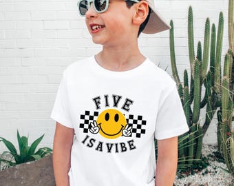 May include: White t-shirt with a black and white checkered pattern, a yellow smiley face with peace signs, and the text "FIVE IS A VIBE".