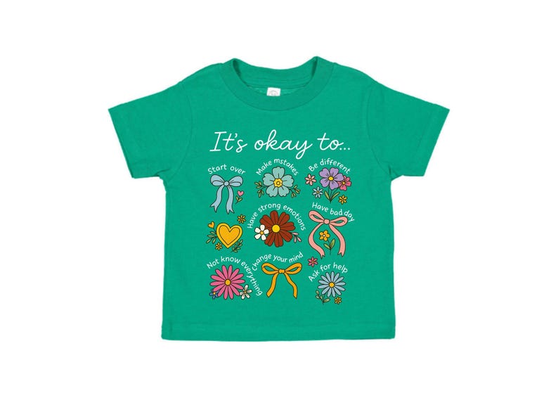 May include: A green toddler t-shirt with the phrase "It's okay to..." and various floral and bow graphics. The shirt features text such as "Start over", "Make mistakes", and "Have a bad day".