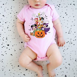 Op de afbeelding: Lichtroze babybody met een Halloween-thema. De afbeelding toont Mickey Mouse, Minnie Mouse, Donald Duck en Goofy in Halloween-kostuums, een pompoen en vleermuizen.